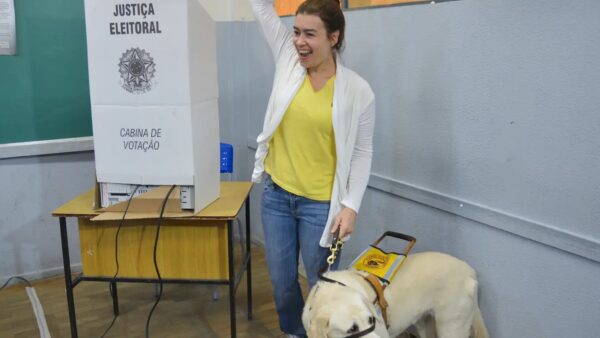 Eleitora com deficiência visual vota acompanhada de cão-guia