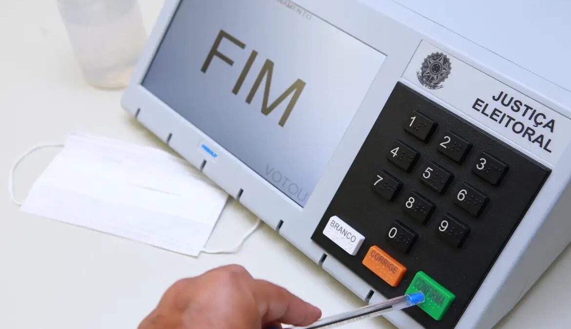 Eleitor vota em urna eletrônica com a mensagem FIM na tela
