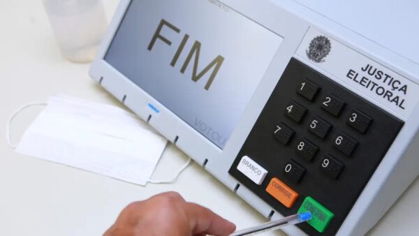 Eleitor vota em urna eletrônica com a mensagem FIM na tela