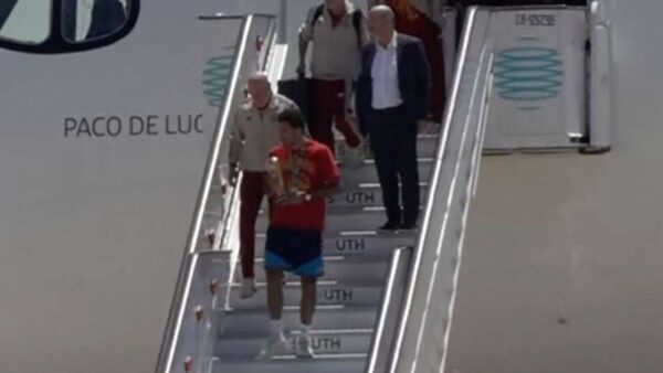 Jogador da seleção espanhola desce escada do avião carregando a taça da Copa do Mundo 2026 ao desembarcar em Madri
