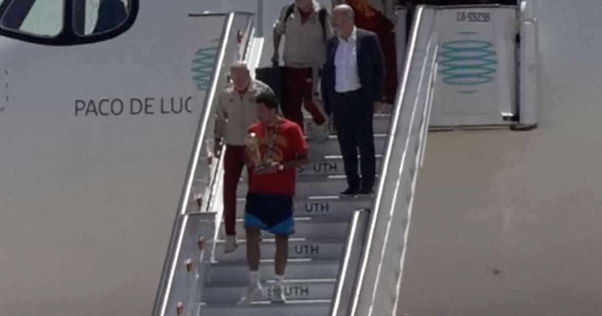 Jogador da seleção espanhola desce escada do avião carregando a taça da Copa do Mundo 2026 ao desembarcar em Madri