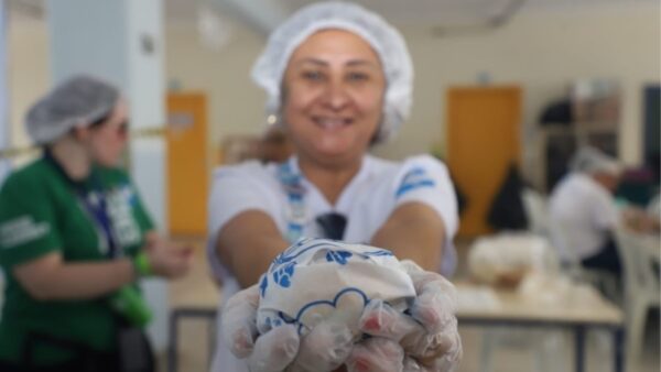 Voluntária entrega lanche durante evento solidário Hamburgada do Bem