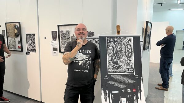 Ilustrador Umberto Daros ao lado de cartaz da exposição O Lado B da Arte em São Caetano