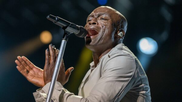 Cantor Seal cantando ao microfone em show ao vivo com luzes coloridas ao fundo