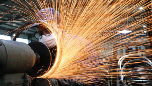 Trabalhador com máscara de proteção operando máquina em usina siderúrgica com faíscas de metal