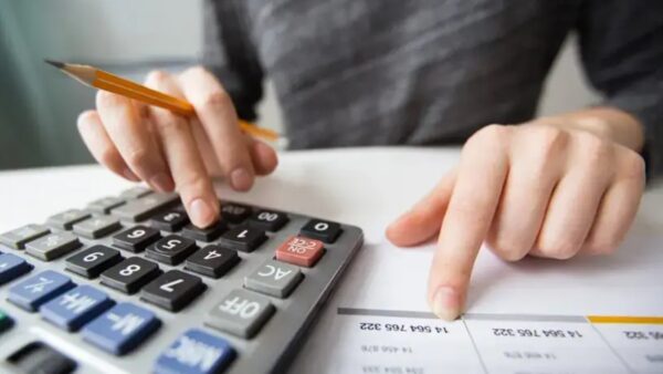 Pessoa calcula impostos com calculadora e documentos fiscais