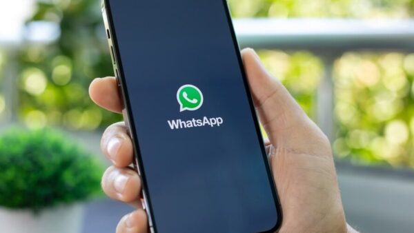 Mão segura celular exibindo tela de abertura do aplicativo WhatsApp