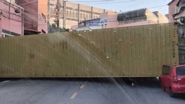 Contêiner de caminhão tombado sobre carro após acidente em ladeira no bairro Inamar em Diadema