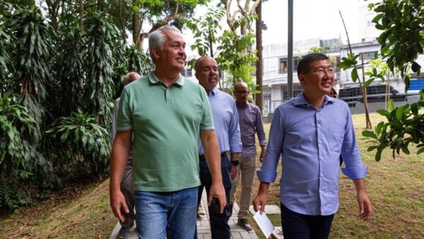 Marcos Michels caminhando ao lado do prefeito Taka Yamauchi e outras autoridades em área verde de Diadema