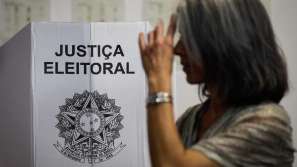 Eleitora vota em urna com identificação da Justiça Eleitoral