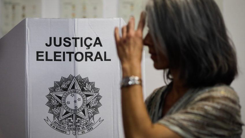 Eleitora vota em urna com identificação da Justiça Eleitoral