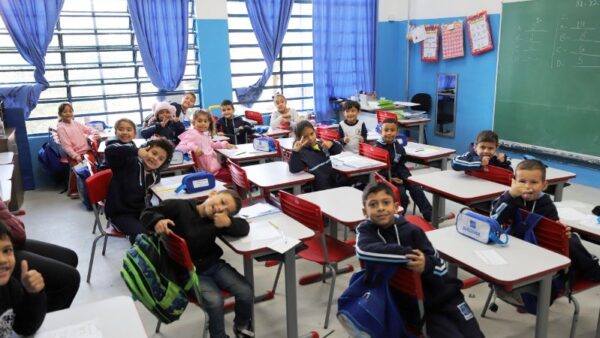 Alunos sorridentes sentados em carteiras de sala de aula em escola municipal de Diadema