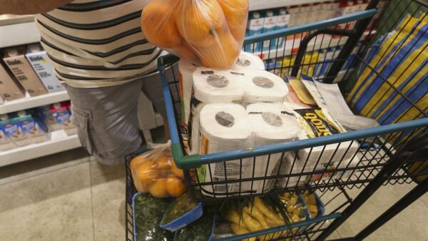 Pessoa colocando produtos em carrinho de supermercado