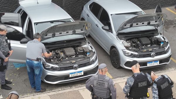 Policiais civis, militares e da ROMU cercam dois carros Volkswagen Polo idênticos apreendidos por clonagem de placa