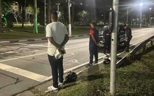 Agentes da GCM e suspeito parados à noite ao lado de motocicleta em via de Diadema