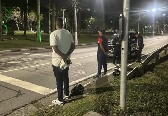 Agentes da GCM e suspeito parados à noite ao lado de motocicleta em via de Diadema
