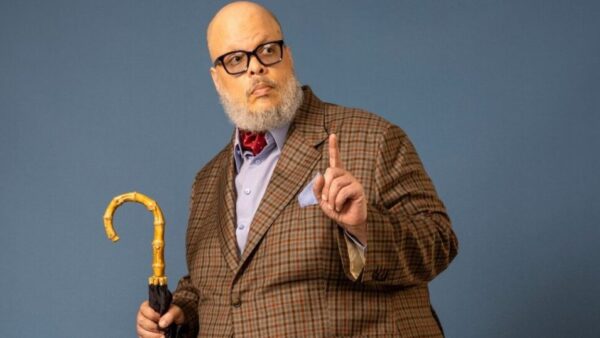 Retrato de Ed Motta com terno xadrez e guarda-chuva