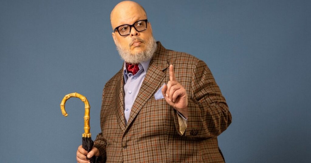 Retrato de Ed Motta com terno xadrez e guarda-chuva