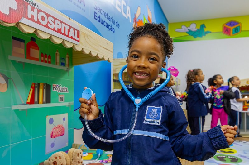Criança com estetoscópio de brinquedo em espaço lúdico de unidade escolar de Diadema