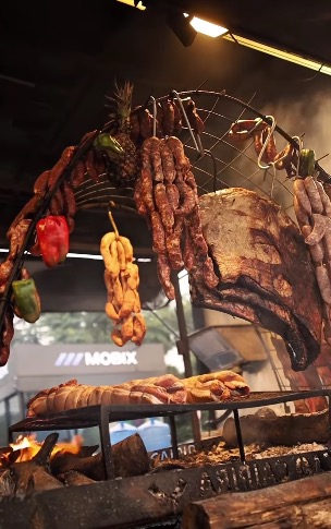 Carnes assadas penduradas em estação de churrasco do Burning Fest em São Bernardo