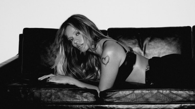 Karol G deitada em sofá em foto de divulgação do álbum