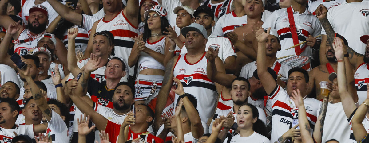 Torcida são-paulina com bandeiras e camisas em arquibancada de estádio