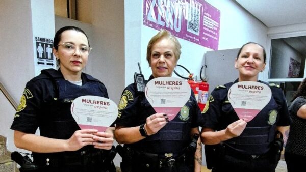 Guardas civis municipais seguram cartazes da campanha Mulheres força que inspira