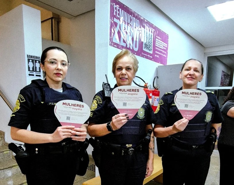 Guardas civis municipais seguram cartazes da campanha Mulheres força que inspira