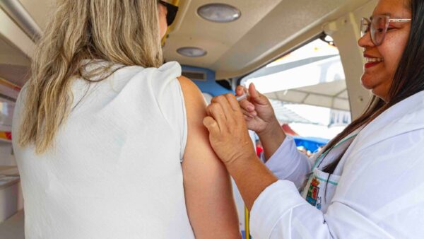 Profissional de saúde aplica vacina contra sarampo em mulher dentro de unidade móvel de saúde
