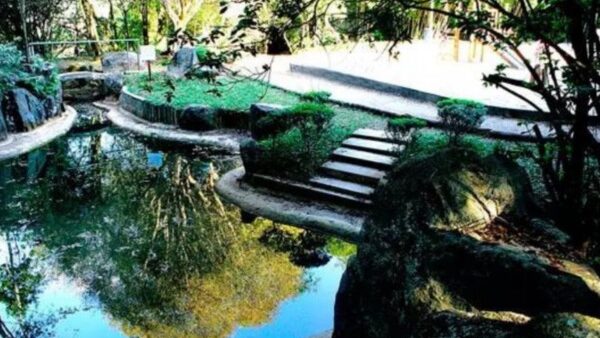 Lago e ponte de pedra no Parque Takebe, em Diadema, cercado de vegetação