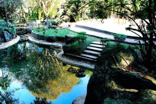 Lago e ponte de pedra no Parque Takebe, em Diadema, cercado de vegetação