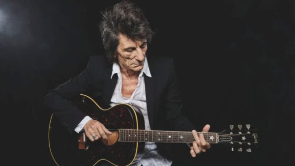 Ronnie Wood tocando violão em foto de divulgação
