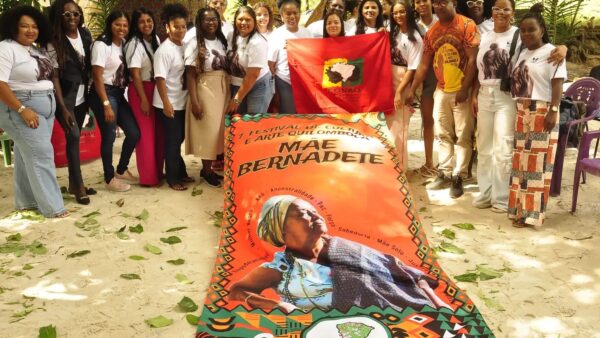 Grupo de mulheres quilombolas posa com bandeira da Conaq e faixa em homenagem a Mãe Bernadete