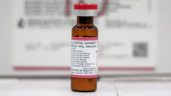 Frasco de vacina contra sarampo, caxumba e rubéola sobre superfície branca