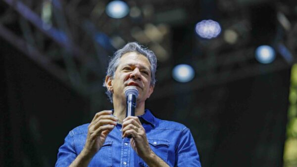 Fernando Haddad discursando ao microfone durante evento de campanha à noite