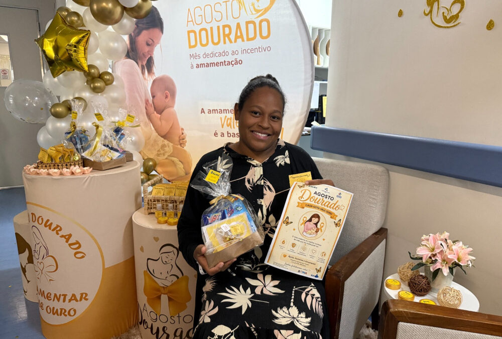 Mãe sorri segurando kit da campanha Agosto Dourado no Hospital Nardini em Mauá