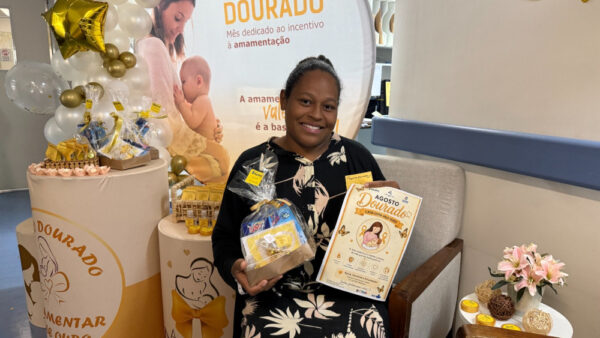 Mãe sorri segurando kit da campanha Agosto Dourado no Hospital Nardini em Mauá
