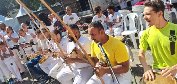 Grupo de capoeira toca berimbau e pandeiro em roda