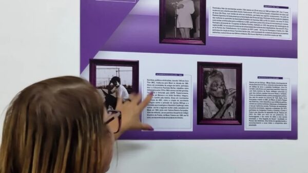 Criança observando painel de exposição sobre trajetória de luta das mulheres no Paço Municipal de Mauá