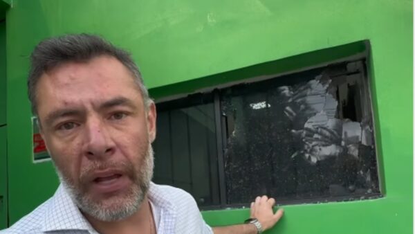 Deputado Fernando Marangoni mostrando janela com vidro estilhaçado por disparos em diretório político atacado em Santo André