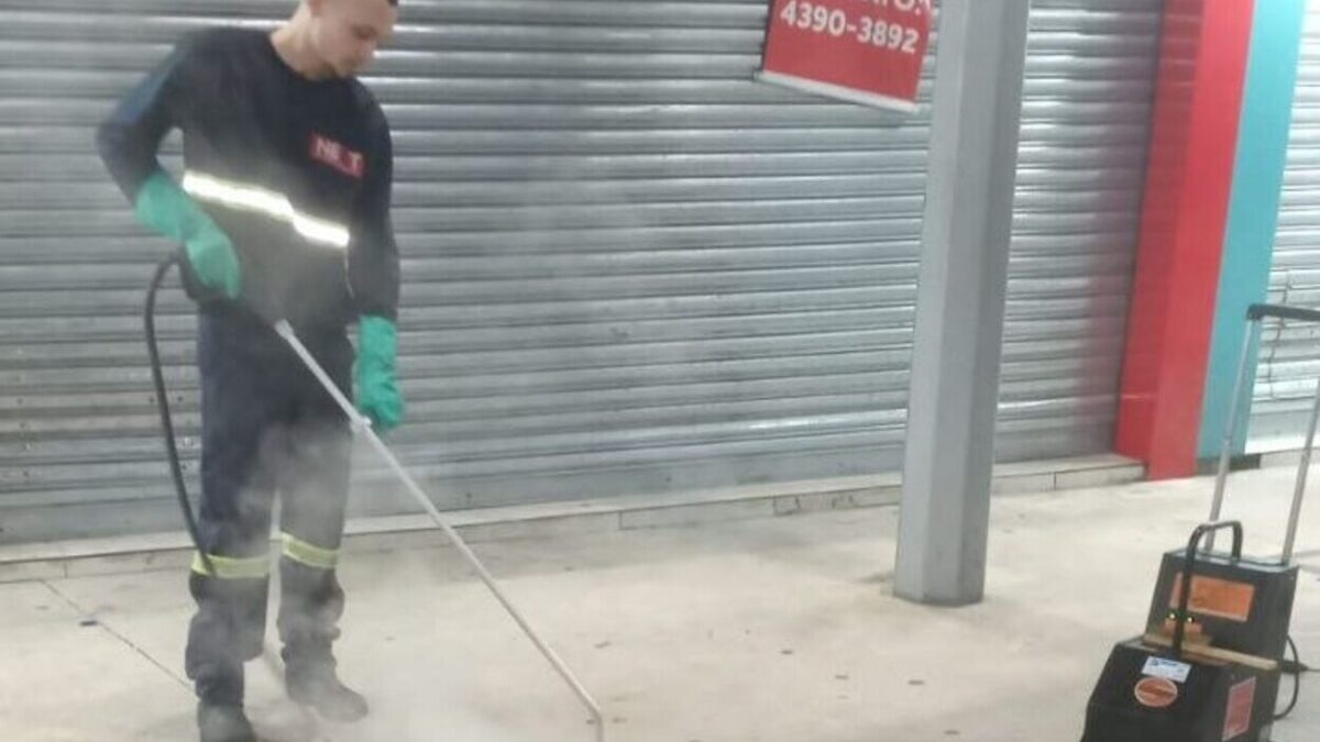 Trabalhador da Next Mobilidade usando máquina a vapor para remover chicletes do piso de terminal em Santo André