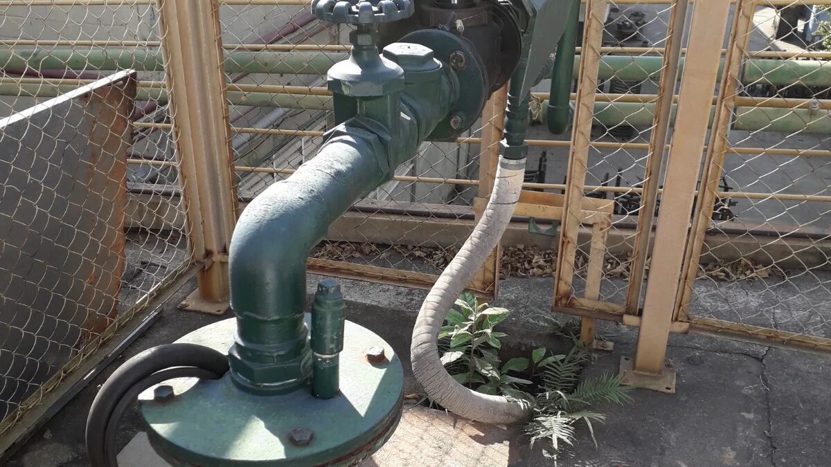 Poço artesiano com tubulação verde e válvula em área cercada por grade em São Bernardo do Campo