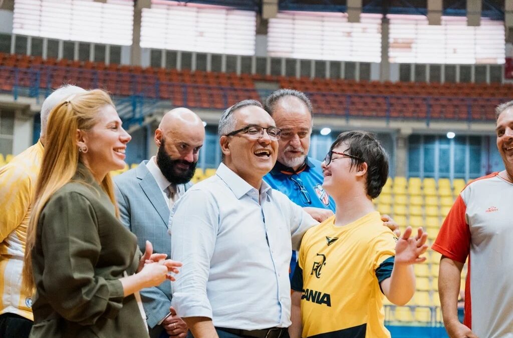 Prefeito Marcelo Lima sorrindo ao lado de atleta com síndrome de Down durante lançamento da Escola de Futsal adaptada em ginásio de São Bernardo