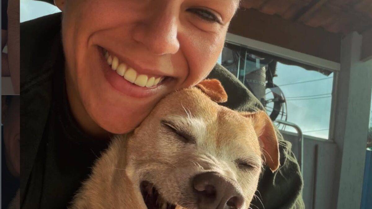 Cantora lírica Juliana Taino sorrindo abraçada com sua cadelinha Fiona
