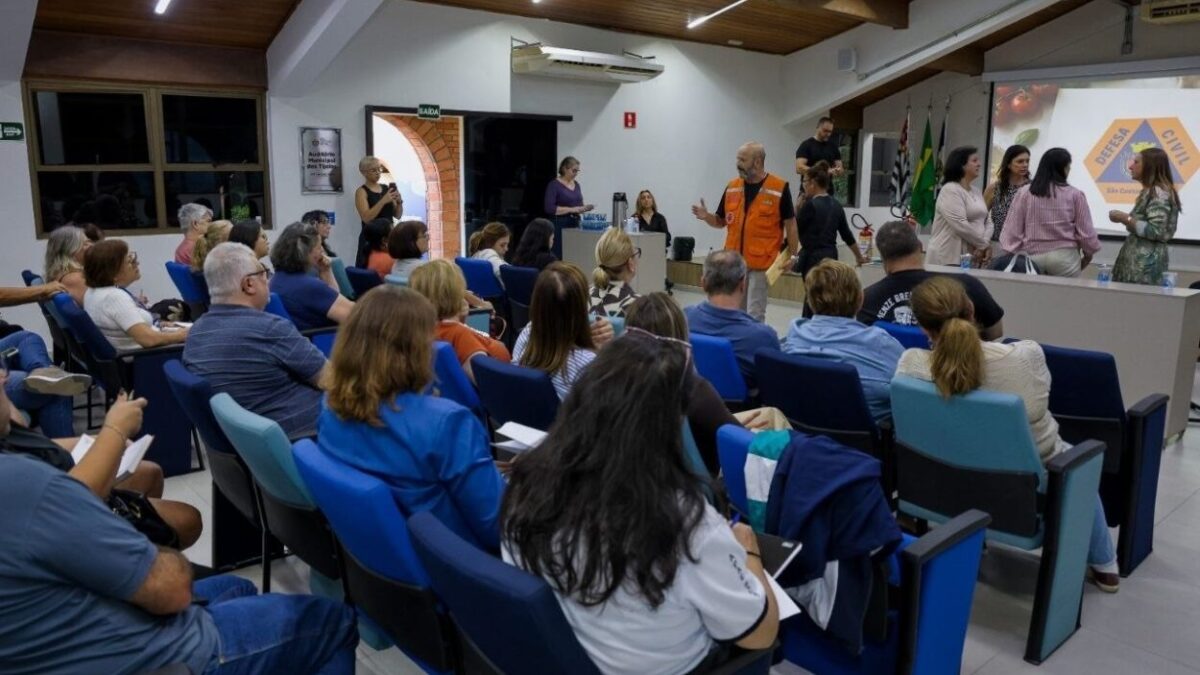 Voluntários sentados em auditório durante treinamento da Defesa Civil de São Caetano para a Festa Italiana