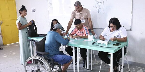 Eleitor em cadeira de rodas é atendido por mesários durante votação