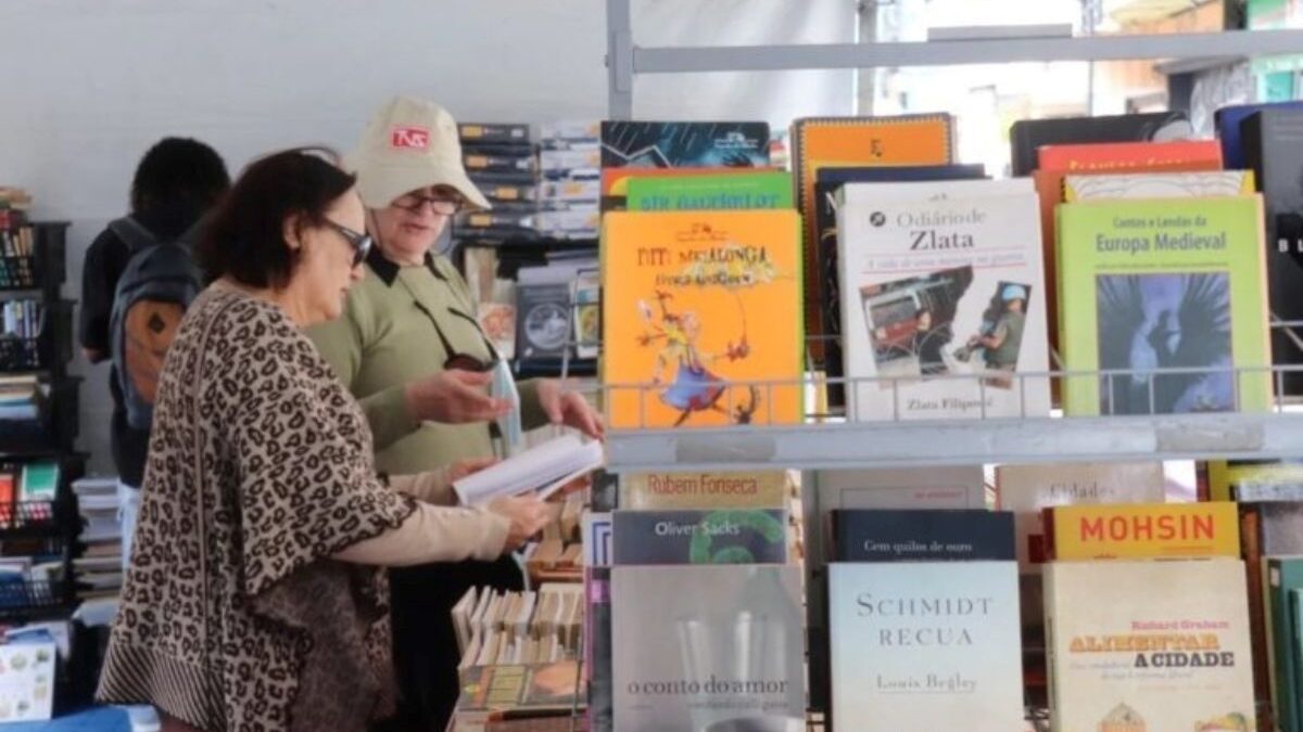 Visitantes observam livros em banca durante feira literária