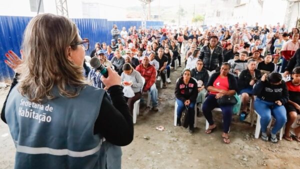 Representante da Secretaria de Habitação de Mauá fala ao microfone para moradores do Jardim Oratório