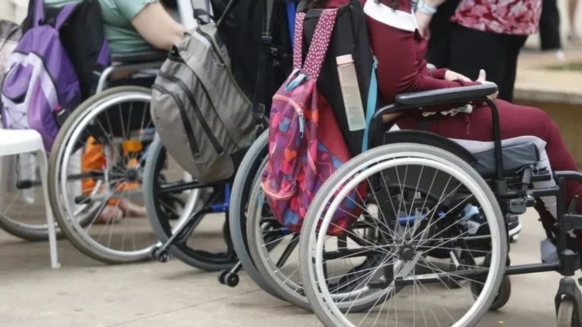 Pessoas em cadeiras de rodas com mochilas, representando a inclusão de pessoas com deficiência
