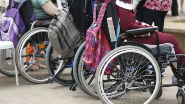 Pessoas em cadeiras de rodas com mochilas, representando a inclusão de pessoas com deficiência